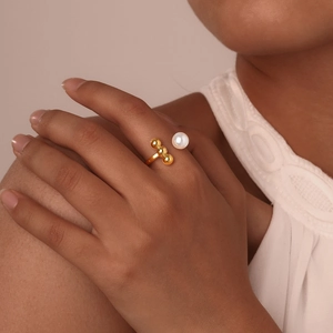 Detailed shot of a gold-plated open ring featuring a white pearl and three gold beads