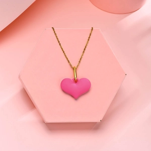 Détail d'un collier avec pendentif cœur rose mat sur un présentoir géométrique