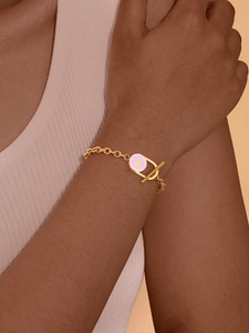 Gros plan du bracelet doré à fermoir OT avec breloque papillon en émail violet