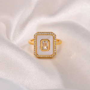 Macro detail of gold geometric ring featuring central zircon and white shell inlay