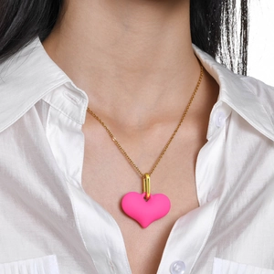 Gros plan d'un collier pendentif cœur rose avec chaîne dorée sur une chemise blanche