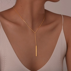 Gros plan d'un collier en Y doré avec pendentif rectangulaire porté par un mannequin