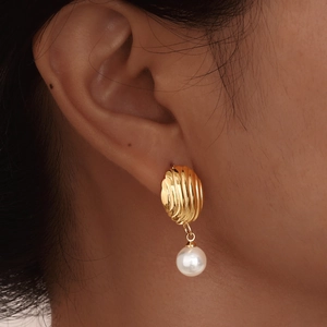 Gold shell textured earrings with white pearls shown on a model for a vintage look