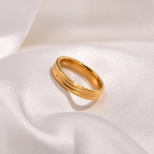 Elegant gold-plated triple-layered stainless steel ring on white silk fabric background