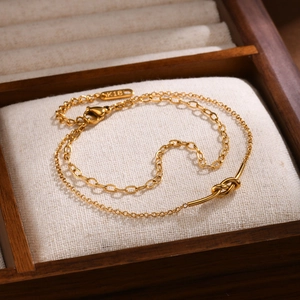 Gold double-layered stainless steel knot bracelet displayed on a wooden jewelry box