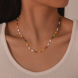 Close-up of a colorful beaded necklace on a model showing rectangular beads and gold accents