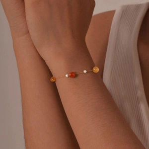 Close-up of a gold link bracelet with amber, agate, and pearls on a woman's wrist