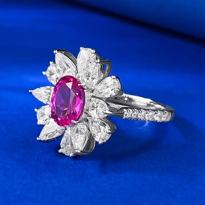 Vue macro d'une bague tournesol avec zircon rose et pétales en cristal sur velours bleu