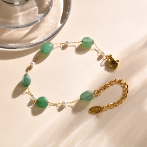 Detail view of gold chain bracelet with green jade stones, pearls and K18 engraving