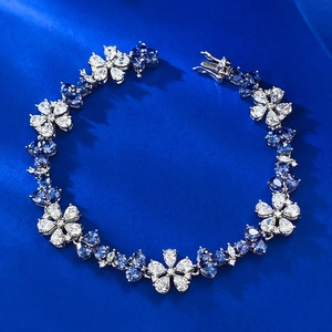 Détail d'un bracelet floral en argent serti de gemmes bleues sur fond de soie bleue
