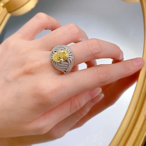 Dettaglio dell'anello ovale con diamante giallo, pavé di pietre e design intrecciato