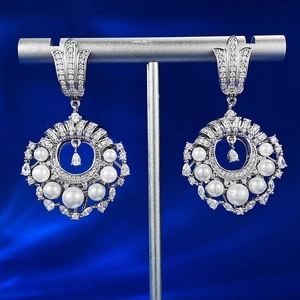 Détail de boucles d'oreilles en argent S925 avec perles et diamants sur soie bleue