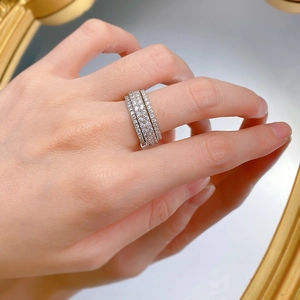 Close-up of triple-row spinning ring with pave diamonds reflecting on a gold mirror