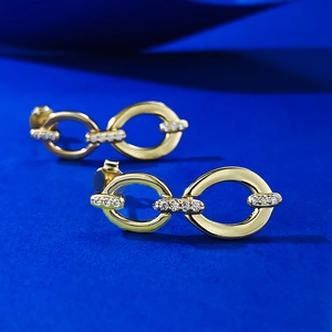 Dettaglio macro di orecchini a catena dorati con pavé di zirconi cubici scintillanti