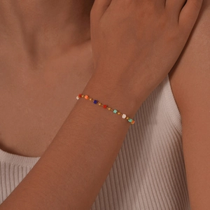Detail shot of a colorful square beaded gold chain bracelet worn on a woman wrist