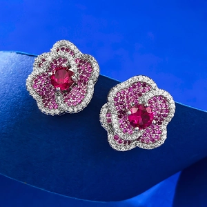 Macro detail of red and pink flower stud earrings featuring multi-layered crystal petals
