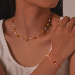 Elegant gold chain jewelry set with white pearls and amber stones on model