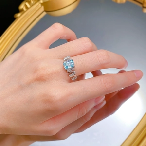Close-up of a silver ring with light blue rectangular stone and geometric band