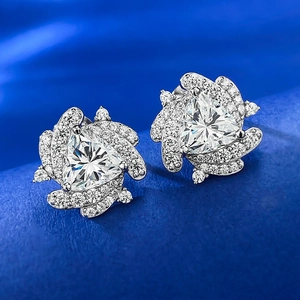 Macro view of triangular stud earrings with pavé stones on blue velvet base