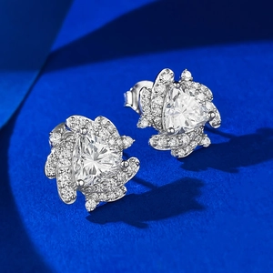 Macro shot of triangle cut stud earrings with halo setting on a textured blue background