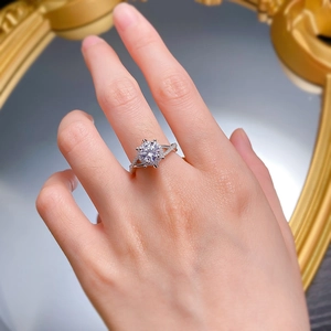 Close-up of a six-prong silver ring with round moissanite and twisted pavé band on finger