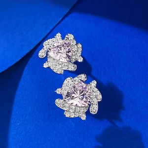 Pink heart-cut gemstone earrings with white diamond halo on blue geometric background