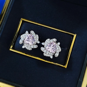 Macro shot of silver swirling stud earrings with pink triangle-cut stone and zircon
