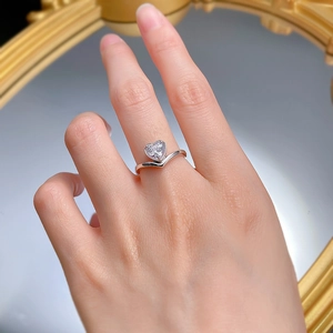 Detail of a 925 silver heart-cut diamond ring on a hand with a vintage gold mirror