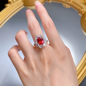 Gros plan d'une bague en argent S925 avec pierre ovale rouge sang de pigeon et halo