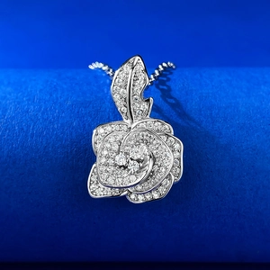 Gros plan du pendentif rose camélia en argent S925 serti de cristaux sur tissu bleu