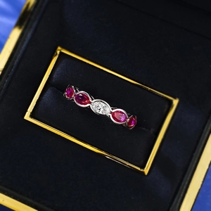 Detailed view of silver ring with oval red gems and white marquise stone in box