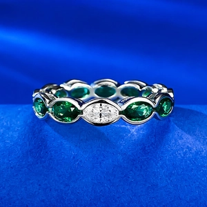 Detailed view of silver ring featuring alternating oval emerald and white gemstones