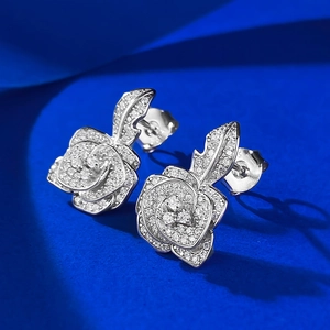 Elegant silver rose stud earrings encrusted with white cubic zirconia on a blue background