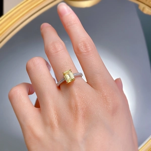 Close-up of radiant cut yellow gemstone ring with pavé diamonds on a hand