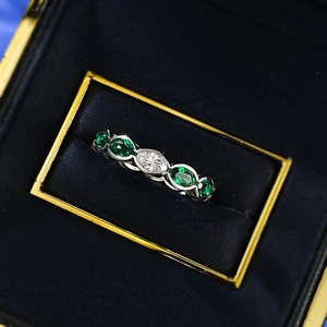 Macro view of S925 silver ring with oval emerald and diamond stones in a black velvet box