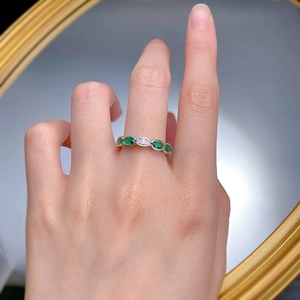 Macro detail of wave-shaped S925 silver ring with green marquise-cut stones on finger