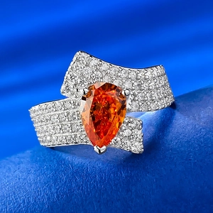 Macro detail of pear-cut orange gemstone ring with multi-row micro-pave diamonds
