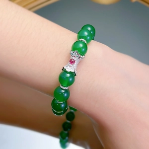 Detail of green chalcedony beaded bracelet with silver flower charm on wrist