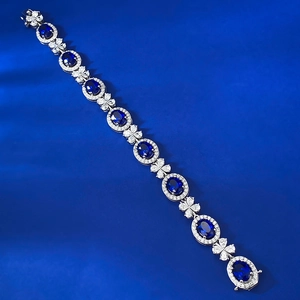 Vue macro du bracelet saphir bleu ovale avec maillons trèfles et halo de diamants