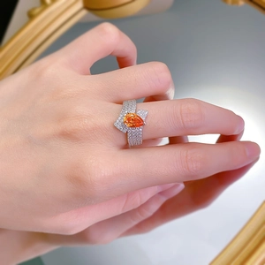 Detail of 925 silver ring featuring a pear-cut orange gem with micro-pave wavy bands