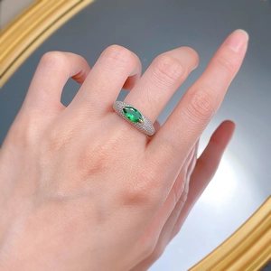 Detail of S925 silver ring featuring marquise-cut green gem and pavé diamond band