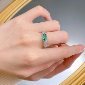 Close-up of a luxury marquise-cut green gemstone ring with pavé diamond band