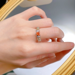 Detail of S925 silver heart ring featuring an orange gemstone and bicolor pavé band