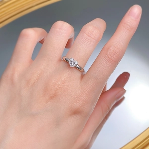 Gros plan d'une bague en diamant en forme de cœur sur un doigt en argent 925