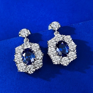 S925 silver oval blue sapphire halo earrings with sparkling diamond surround on blue background