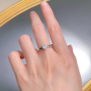 Détail macro d'une bague en argent 925 avec pierre étincelante en forme de cœur au doigt