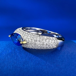 Macro shot of marquise-cut blue gemstone with gold prongs on a diamond-paved band