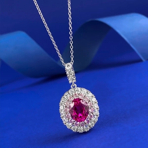 Oval red gemstone necklace pendant with double halo diamond setting on blue silk