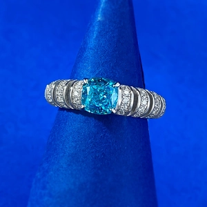 Macro view of blue cushion-cut gemstone set in 925 silver ring with side pavé diamonds