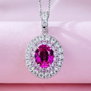 Macro shot of oval rubellite pendant with double halo stones on pink velvet background